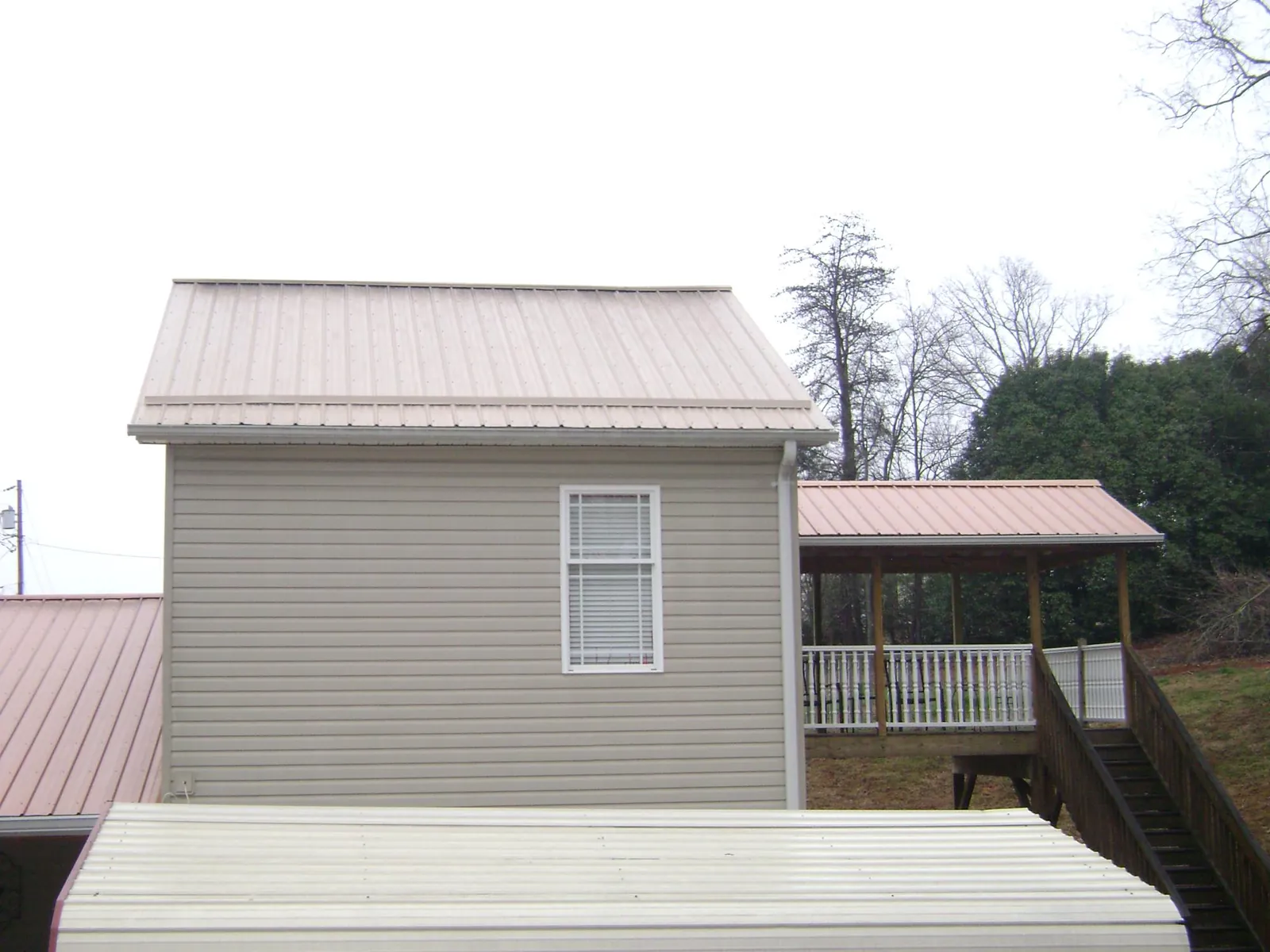 Tan metal roofs on a two story addition and attached porch, from a Roof Replacement job in Monterey